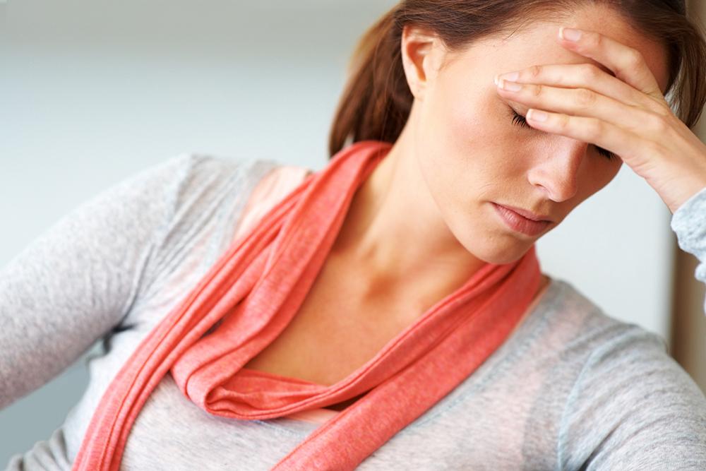 Woman holding her forehead, frowning because she has a headache